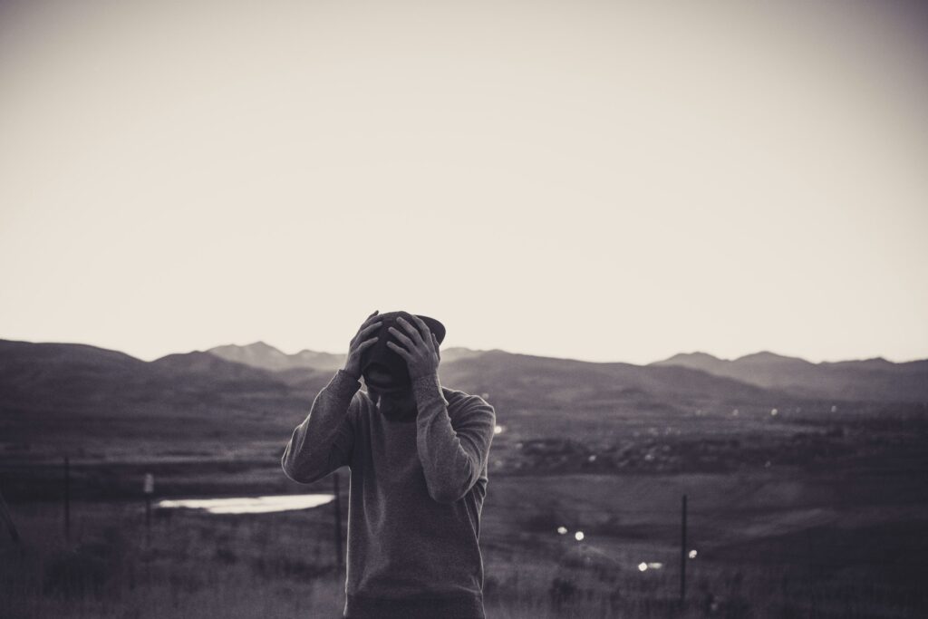 grayscale photo of man holding cap
