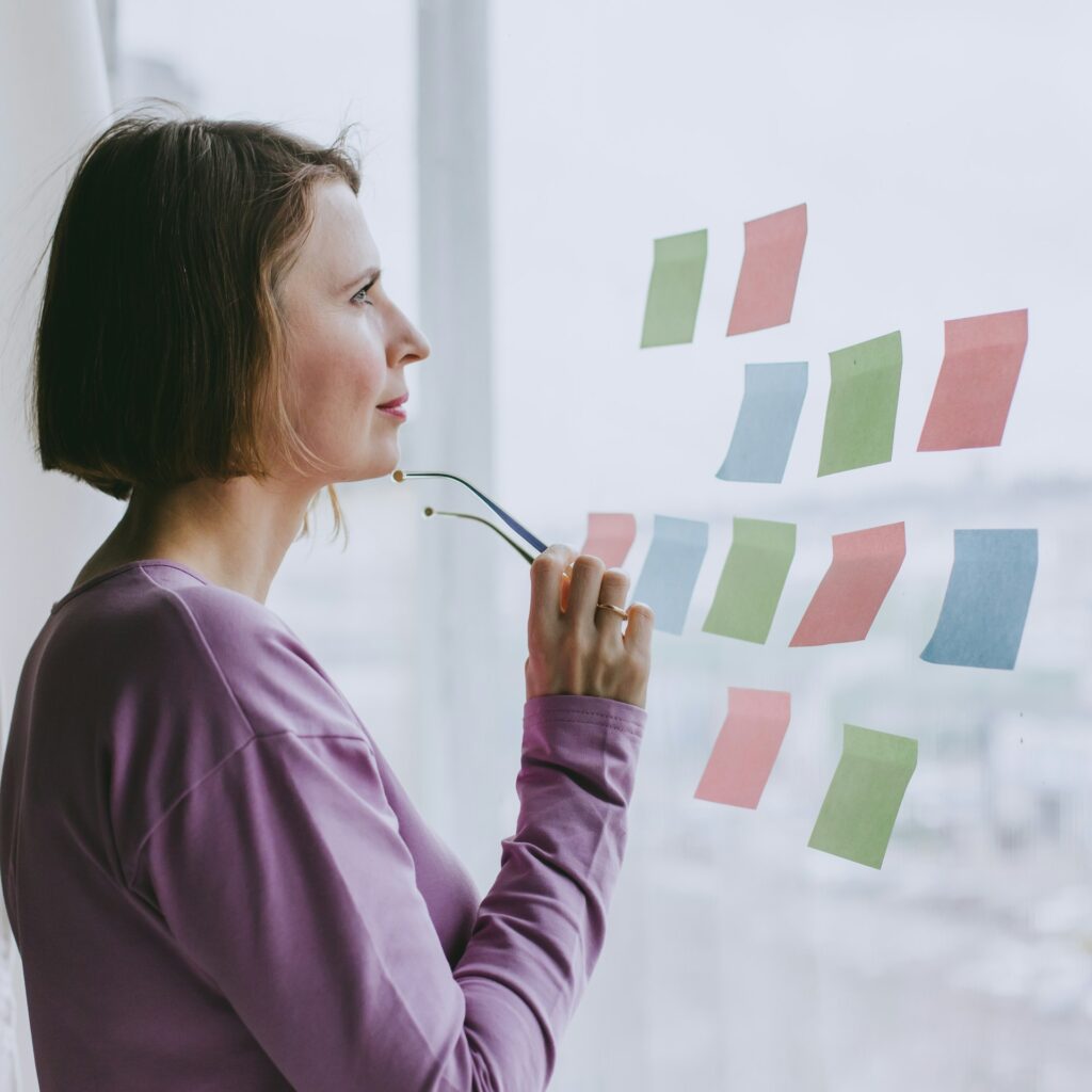 a woman looking out a window with sticky notes on it
