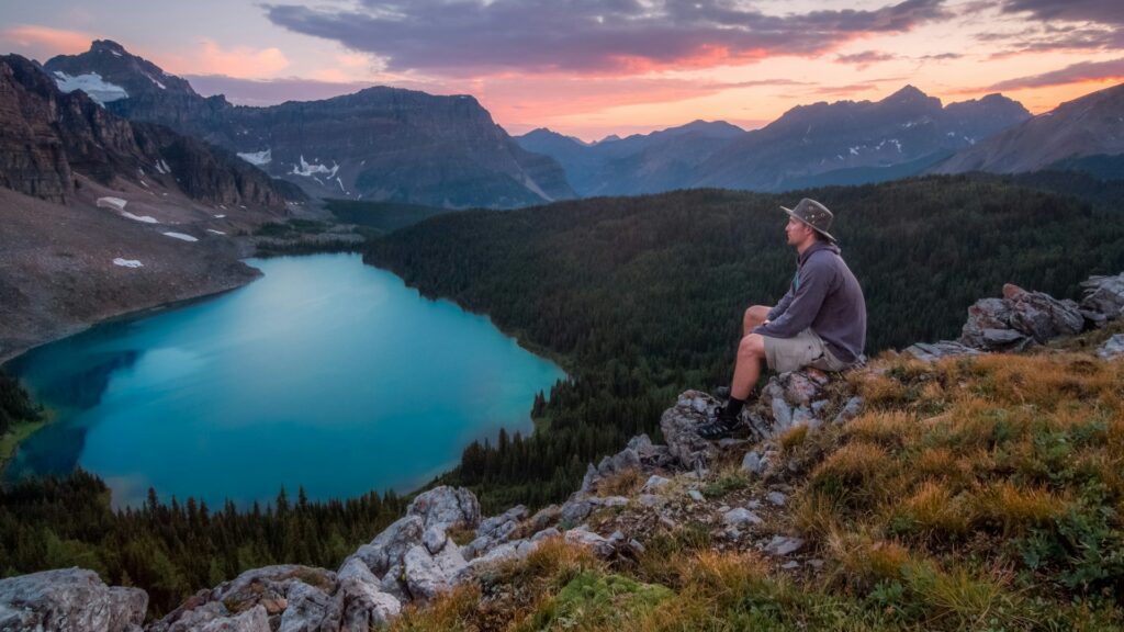 man looking on mountain sitting on rock
