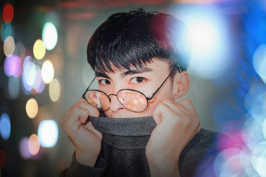 photography of man in gray sweater covering his mouth