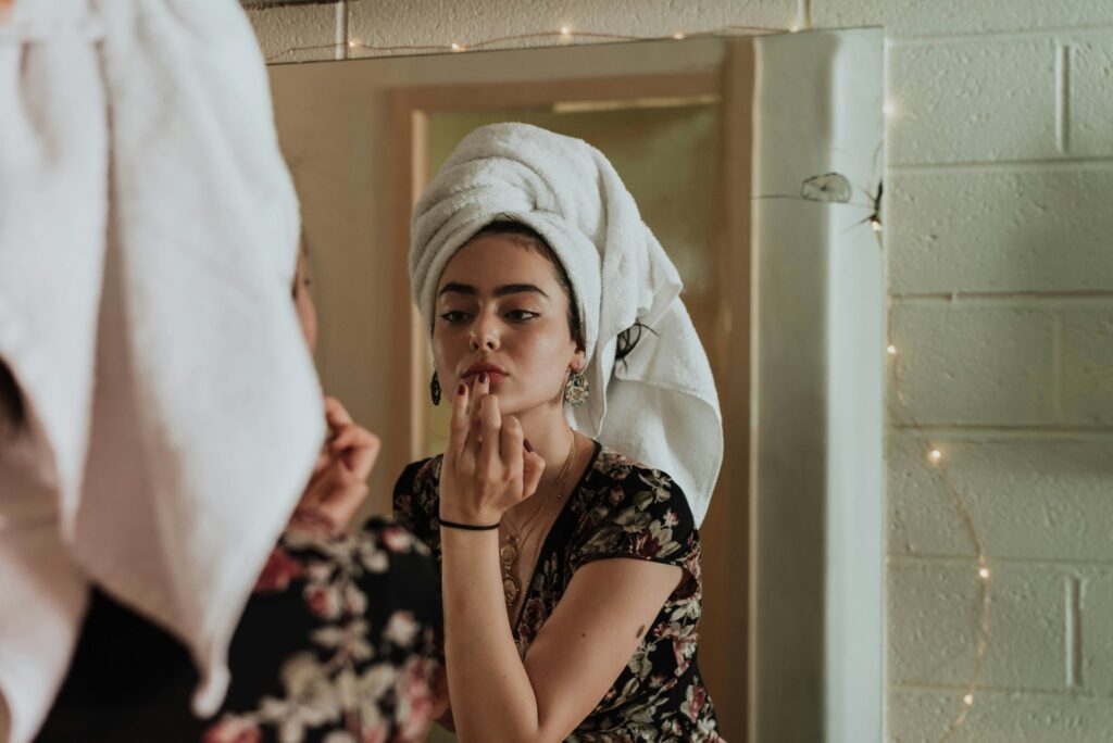 woman putting makeup in front of mirror

