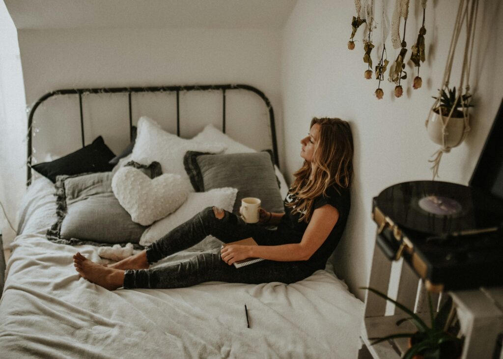 woman leaning on wall while sitting on bed
