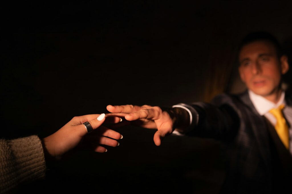 person in black long sleeve shirt holding hands with orange light

