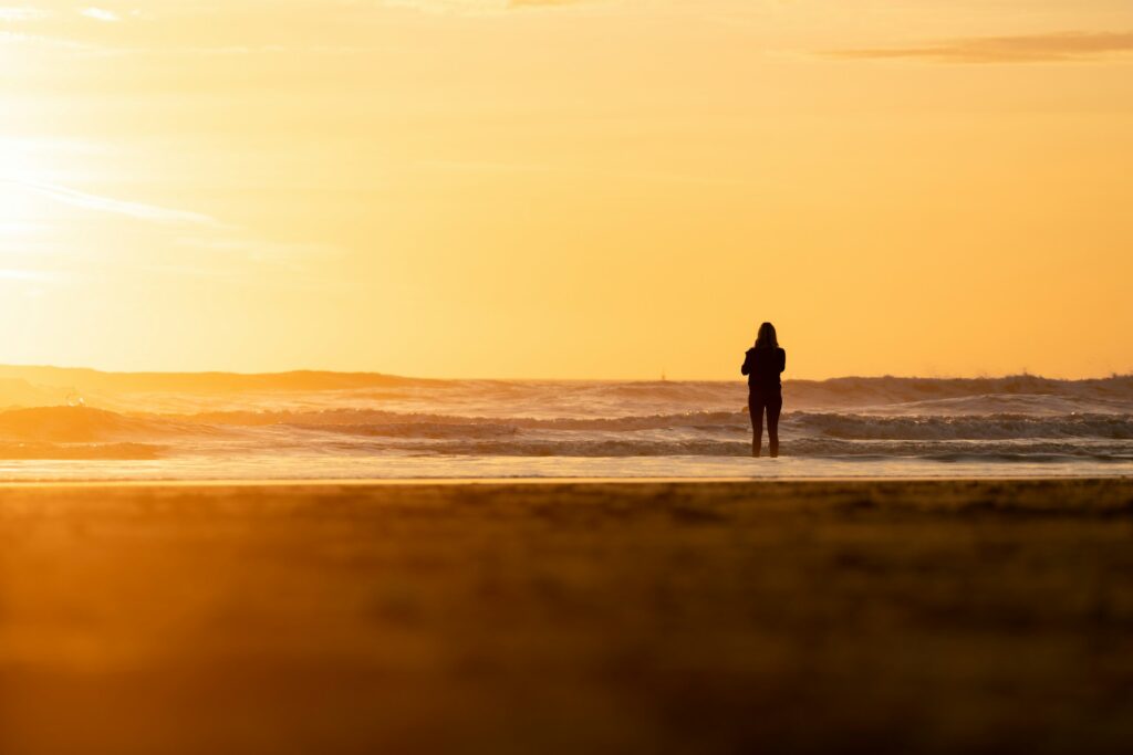 silhouette of man and woman walking on beach during sunset
