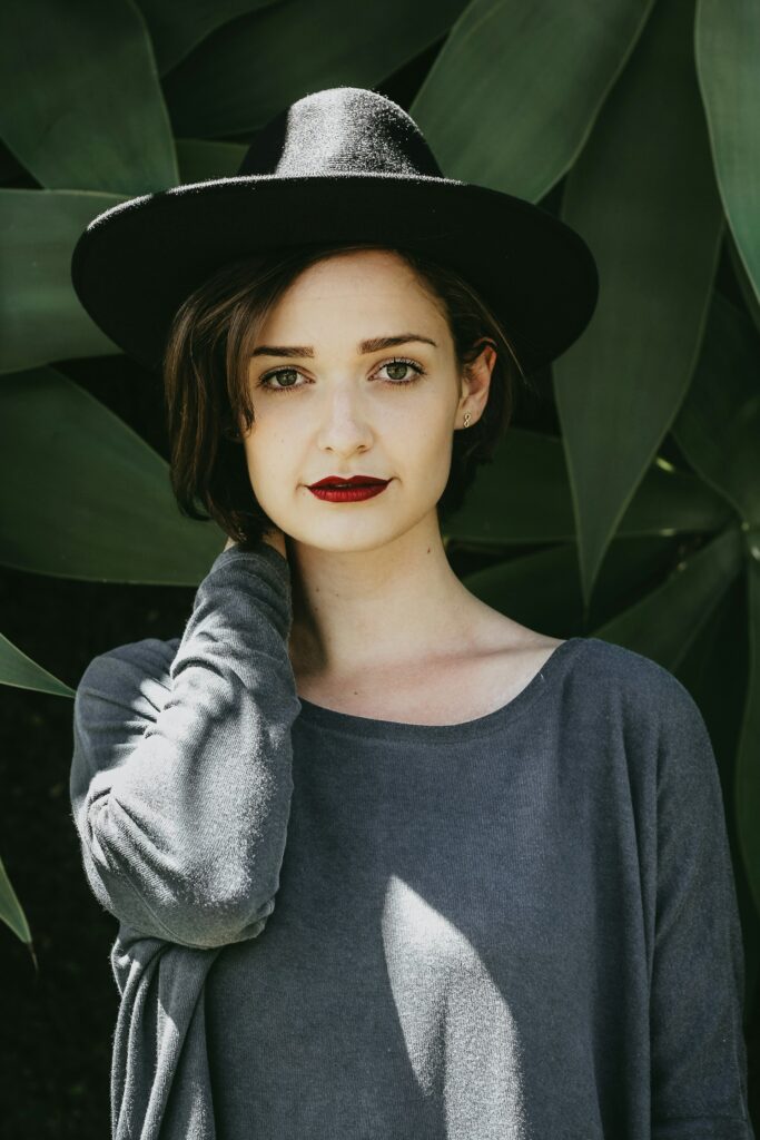 woman standing near trees wearing black hat
