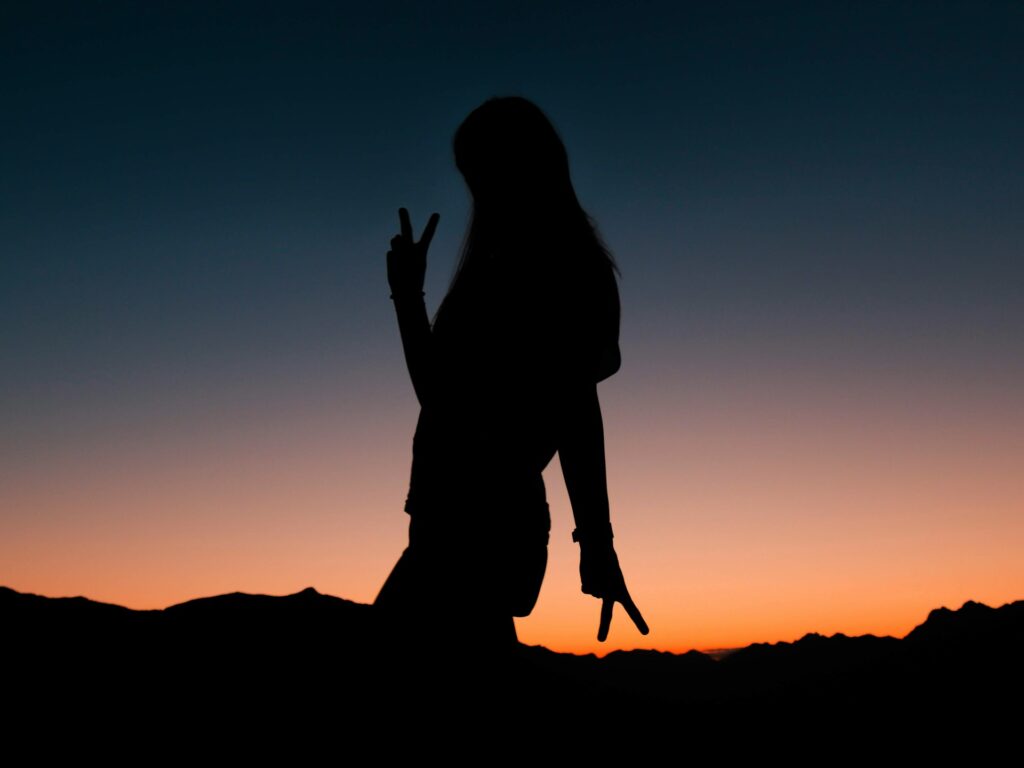 silhouette of woman raising her hands during sunset
