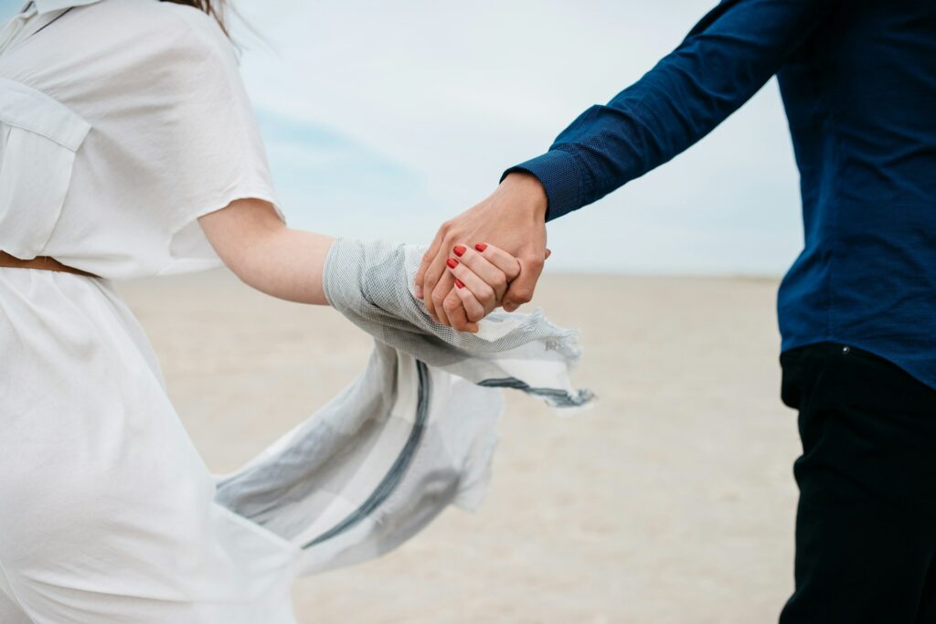 man and woman holding hands together in field during daytime
