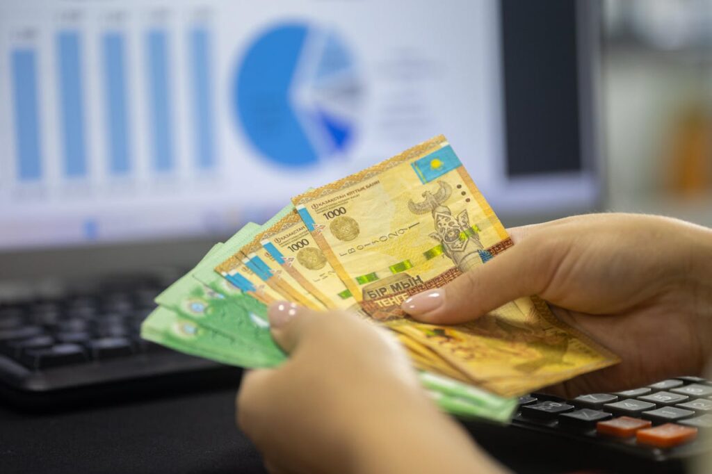 Kazakhstan tenge notes with financial graphs in background