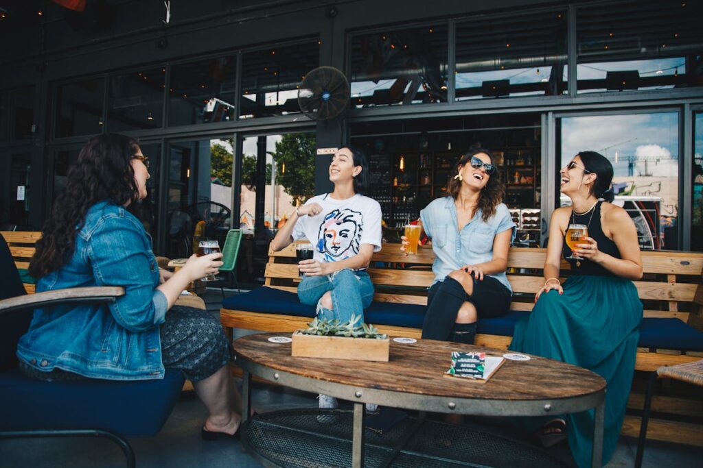 Four Women Chatting While Sitting on Bench
