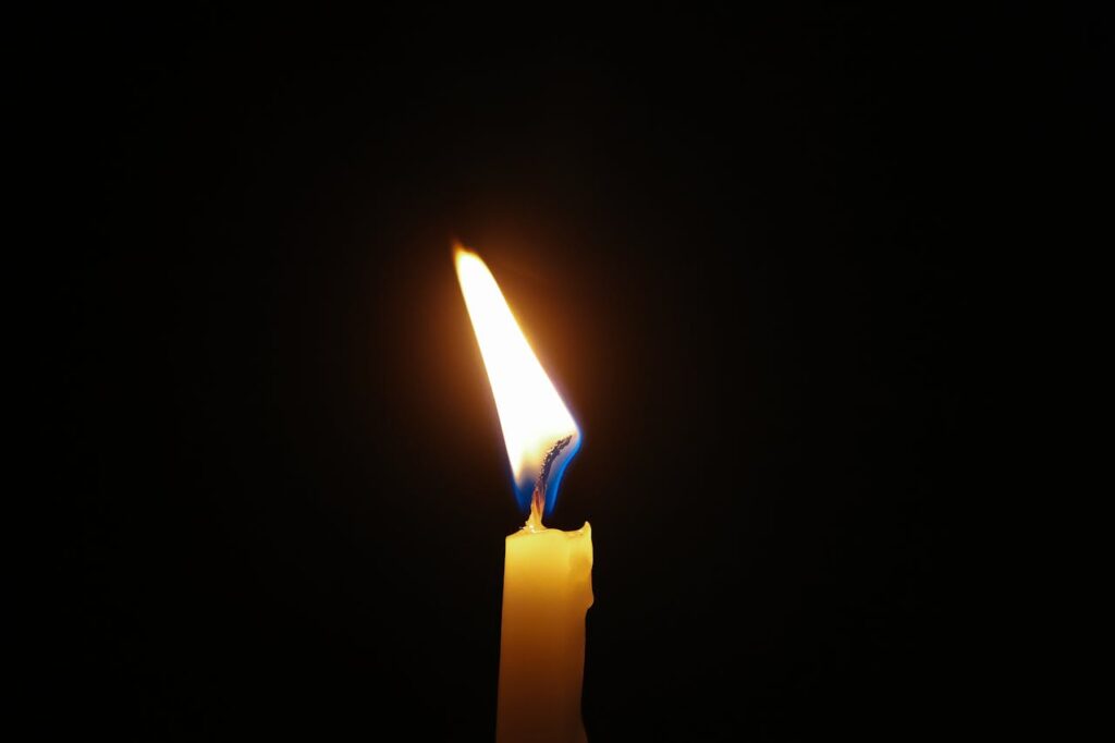Single Candle Flame in Dark Room
