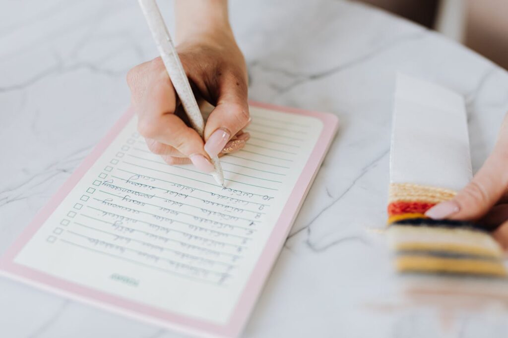 Hand Holding a Pen and Writing Notes on Paper
