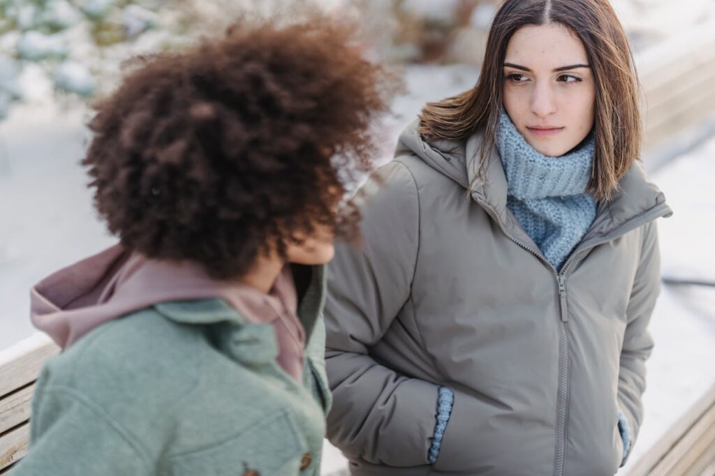 Serious woman sitting on bench with friend
