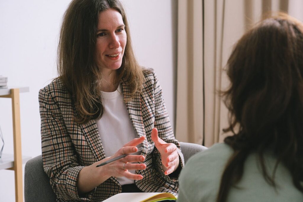 Positive woman sitting with notebook and talking with female