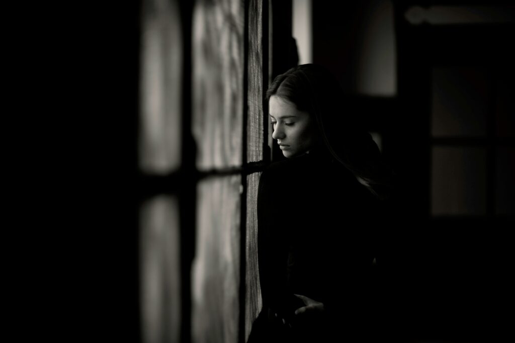 a woman leaning against a wall in a dark room
