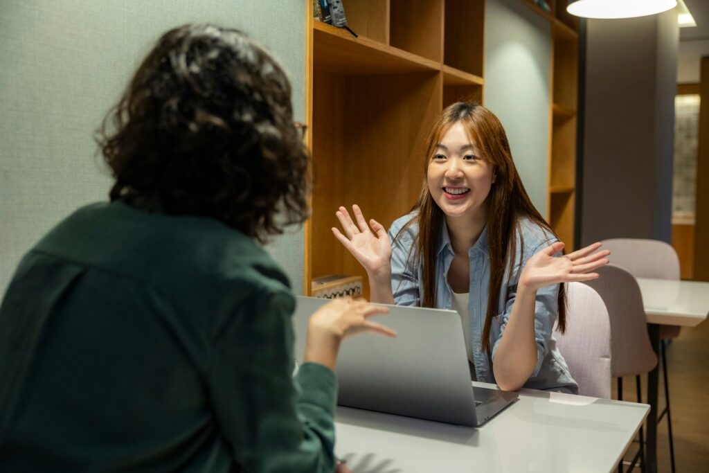 a woman sitting at a table talking to another woman
