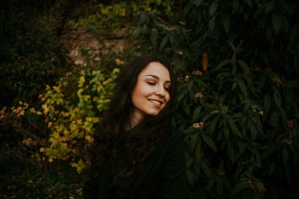 a person smiling in front of a bush
