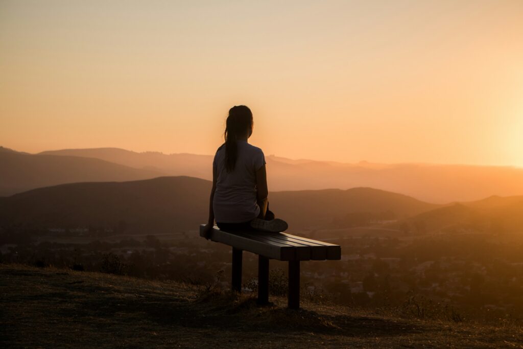 woman sitting on bench over viewing mountain
