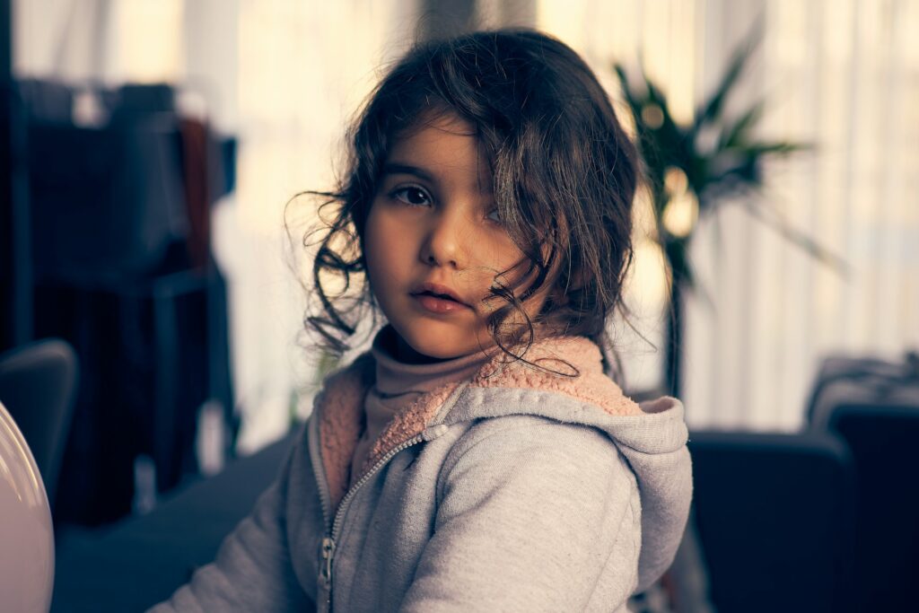 a little girl sitting on a couch with her hair blowing in the wind