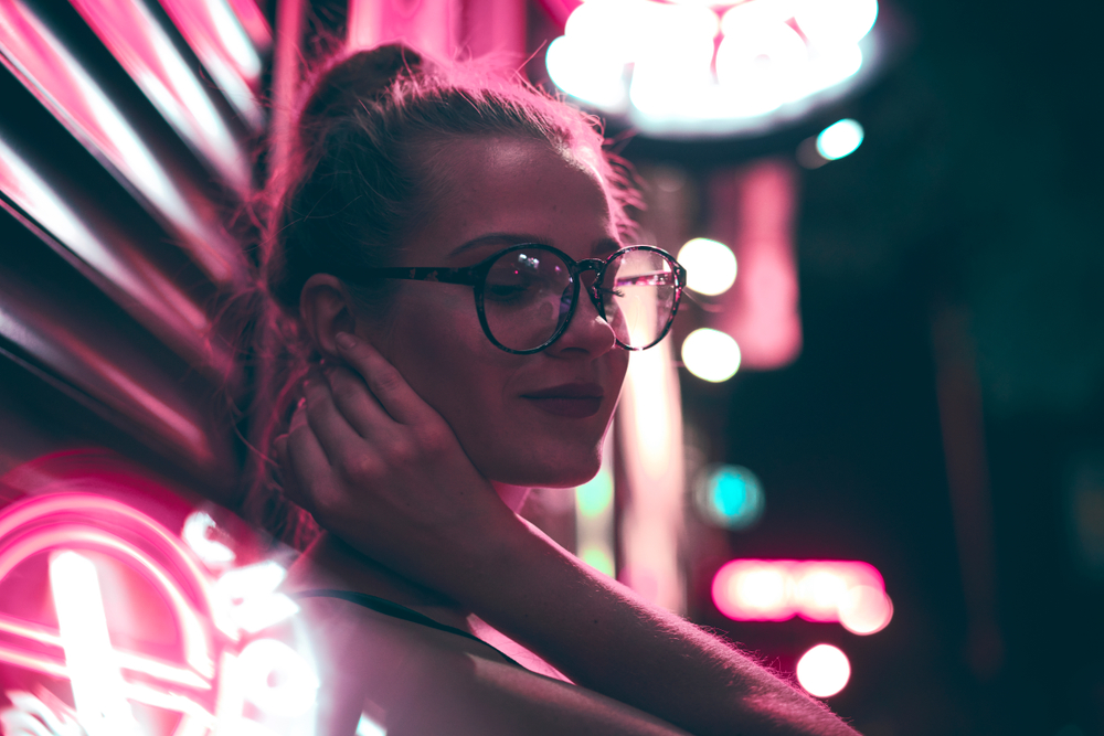 Cute girl at night on the street. Shop signboards