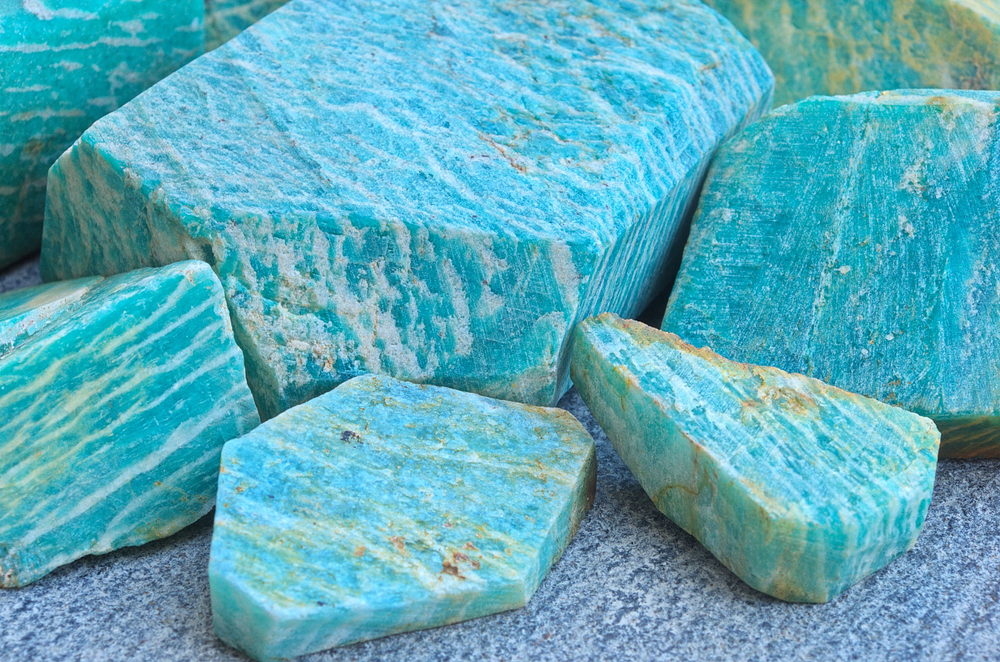 Close-up of pile of natural rocks amazonite (blue and green microcline feldspar) mineral stone. Amazonite raw stones as a background. Selective focus.