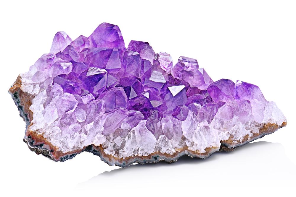 Violet Crystal Stone macro mineral. Purple rough Amethyst quartz crystals geode on white background, Uruguay