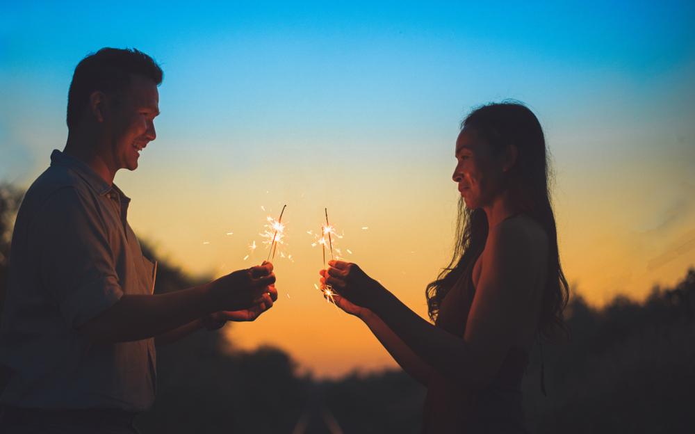 happy couple lighting sparklers and enjoying.Couple holding a burning sparklers