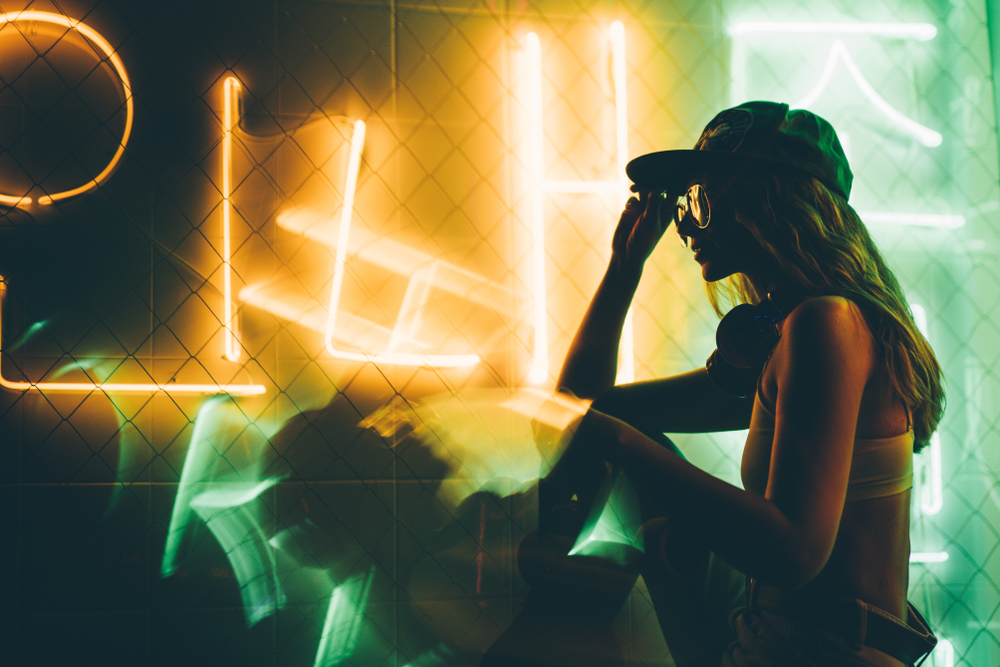 Hip-hop girl in cap in neon light. Fashion portrait of modern young woman in cap and sunglasses.