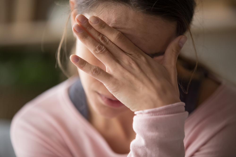 Sad tired young woman touching forehead having headache migraine or depression, upset frustrated girl troubled with problem feel stressed cover crying face with hand suffer from grief sorrow concept
