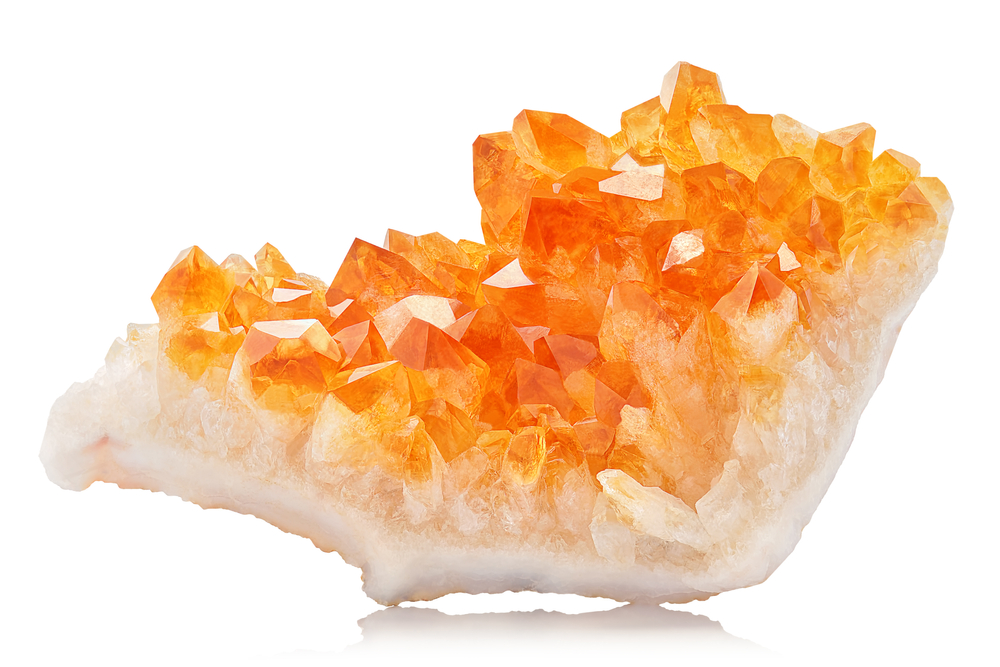 Extreme sharp and detailed closeup macro of amazing orange Citrine Quartz Crystal mineral stone cluster isolated on white background. Natural raw translucent shiny specimen of yellow crystal rock.
