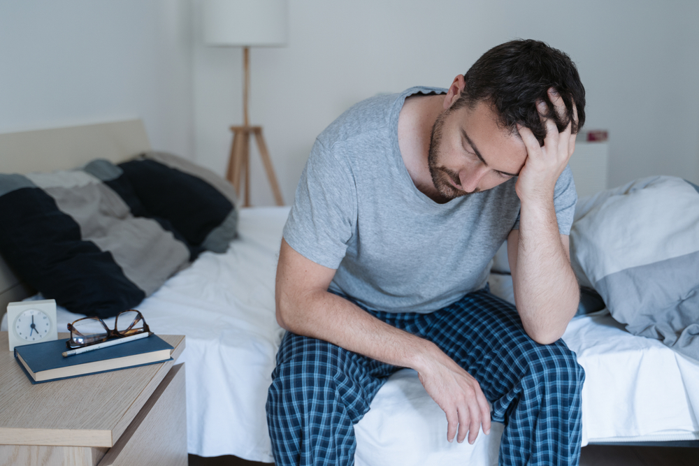 Restless man waking up early with headache after rough night