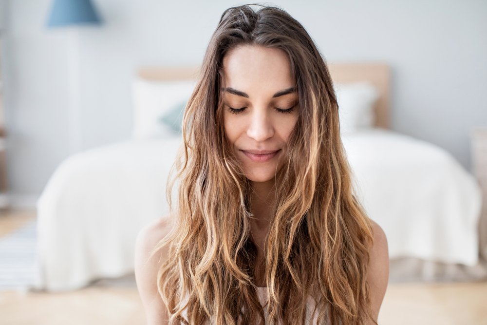 Beautiful authentic woman with closed eyes practices yoga at home, relaxation and meditation.