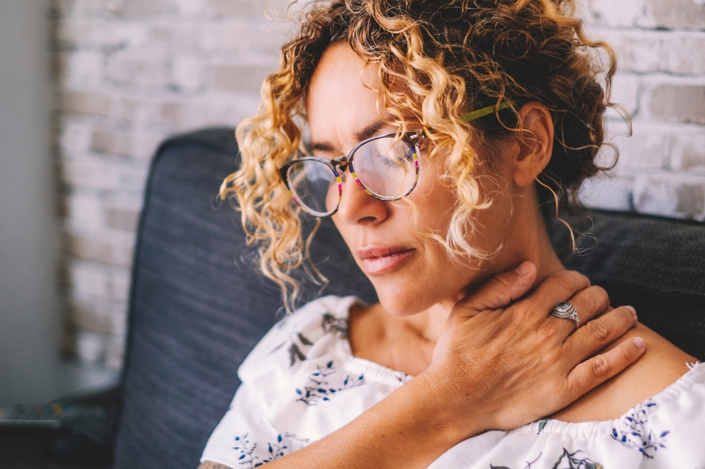 Sick middle age adult young women touching the neck have shoulder and neck pain.Healthcare and medicine concept. Female people suffering shoulder disease at home sitting on the sofa

