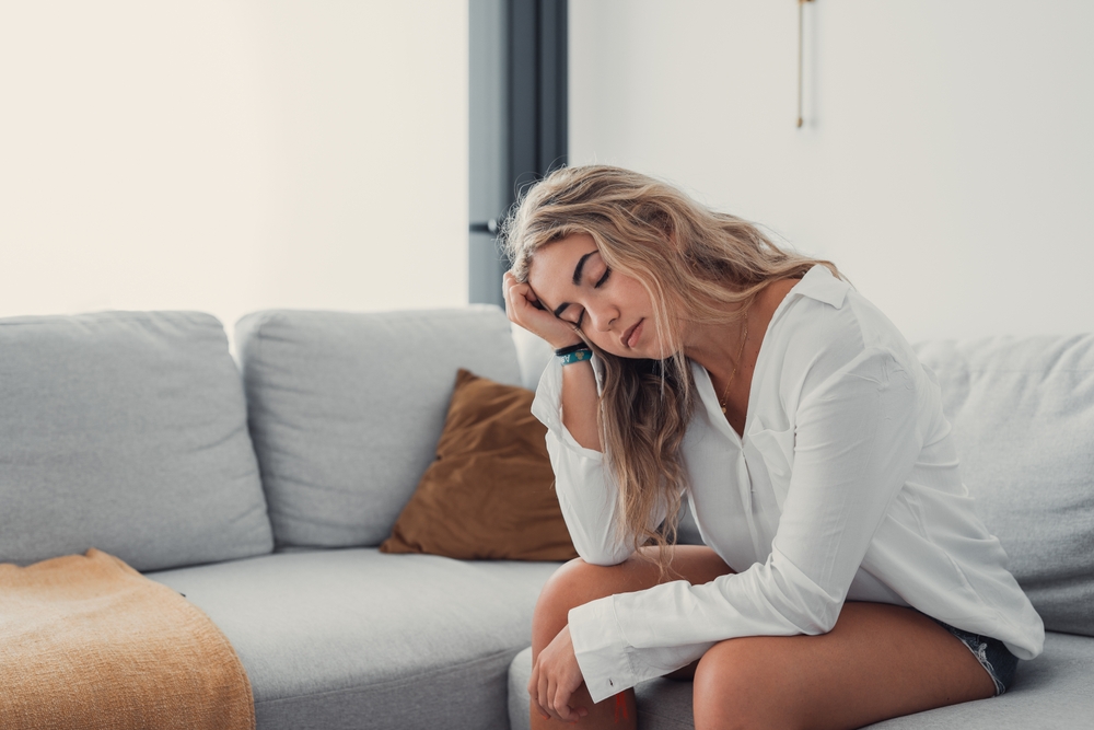 Depressed or tired teen girl feeling stress headache hurt pain sitting alone at home, upset sad heartbroken young woman regret pregnancy or abortion, troubled with problem or psychological trauma
