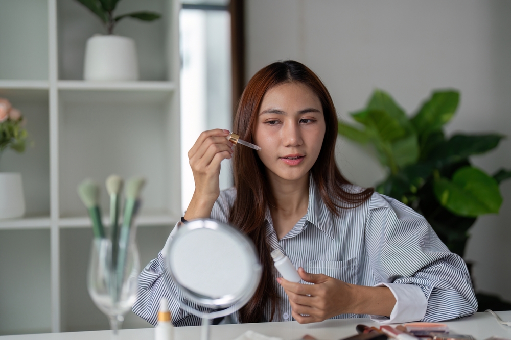 Beauty and Serum Application. A woman applying serum to her face, highlighting her dedication to skincare.