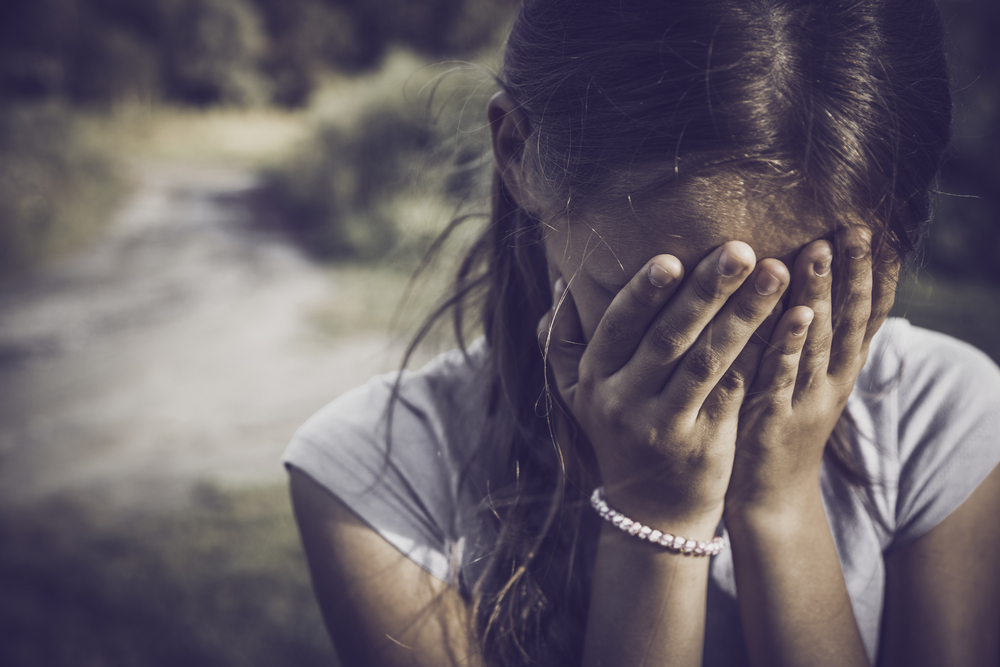 close-up portrait of a girl crying and covering her face