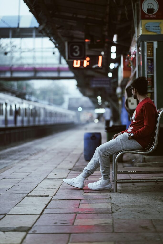 a man sitting on a bench at a train station
