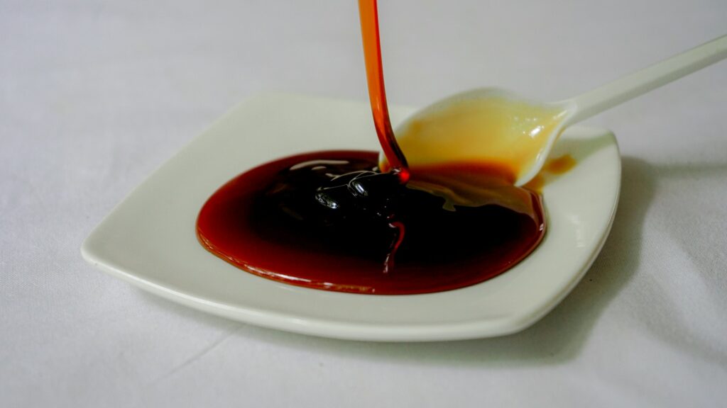 a spoon is pouring sauce on a white plate
