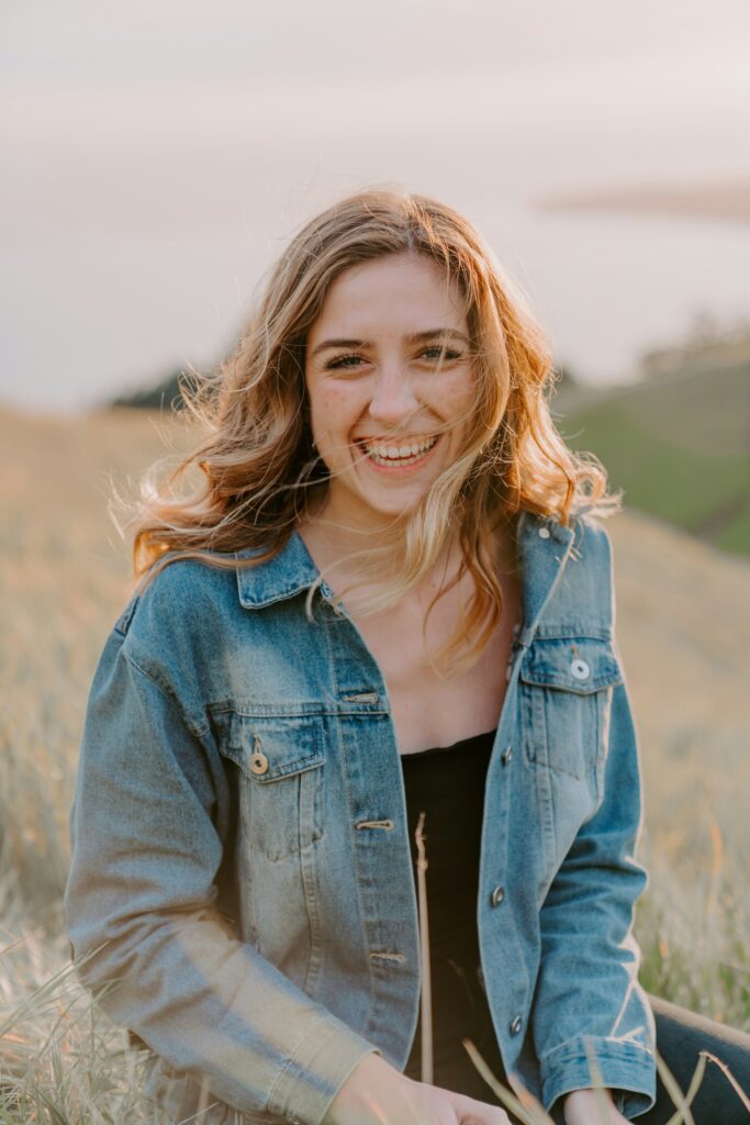 smiling woman sitting on grass during daytime
