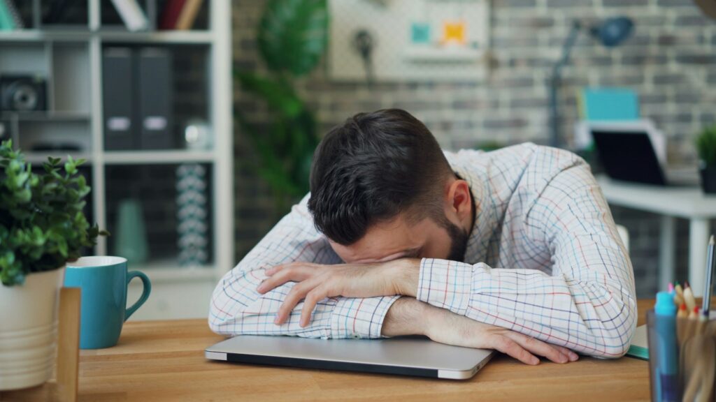 a man sitting at a desk with his head in his hands
