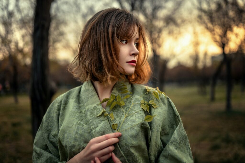 a woman in a green dress standing in a park
