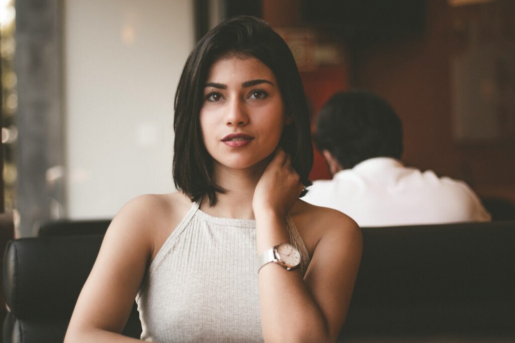 woman wearing gray spaghetti strap shirt sitting on black leather sofa close-up photo
