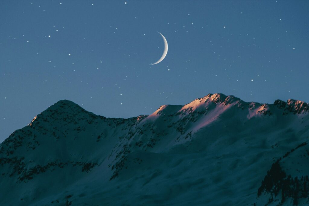 crescent moon above mountain
