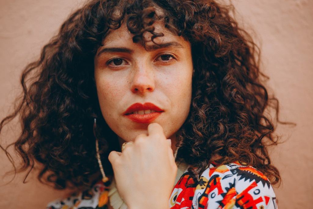 A woman with curly hair posing for a portrait
