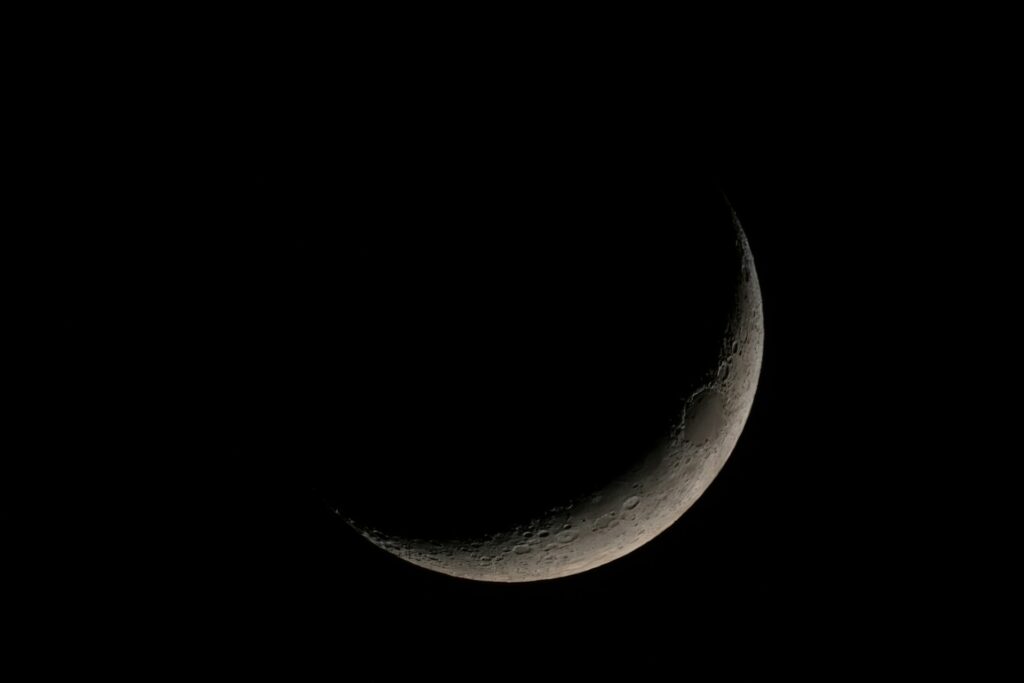 the crescent of the moon in the dark sky
