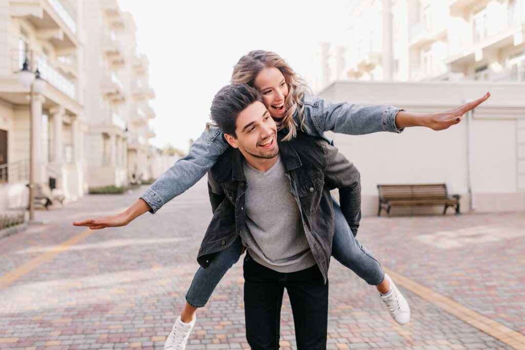 A man riding on the back of a woman on a skateboard