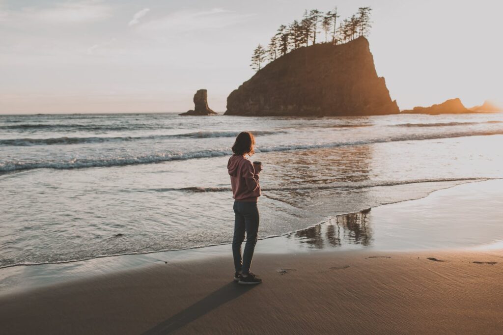 Photo of Woman Standing on Seashore During Sunset

