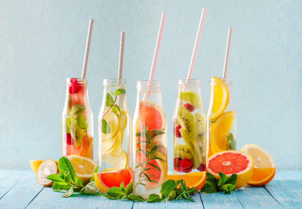 Variety of fruit infused detox water in small bottles. Set of refreshing summer drinks. Healthy diet eating concept.
