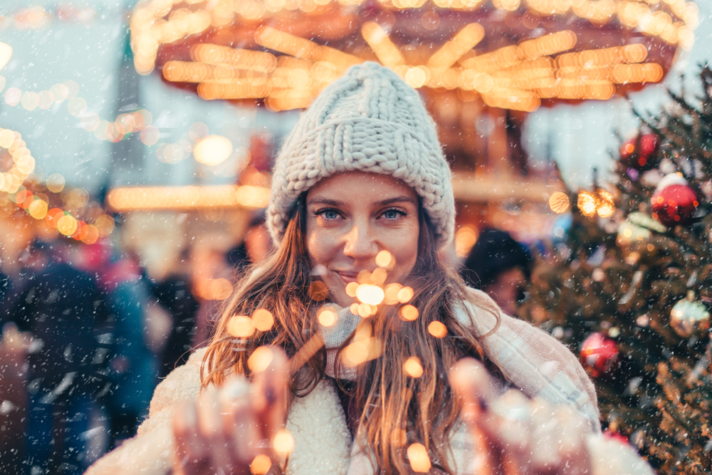 Girl walking in Christmas market decorated with holiday lights in the evening. Feeling happy in big city. Spending winter vacations in Red square, Moscow, Russia.