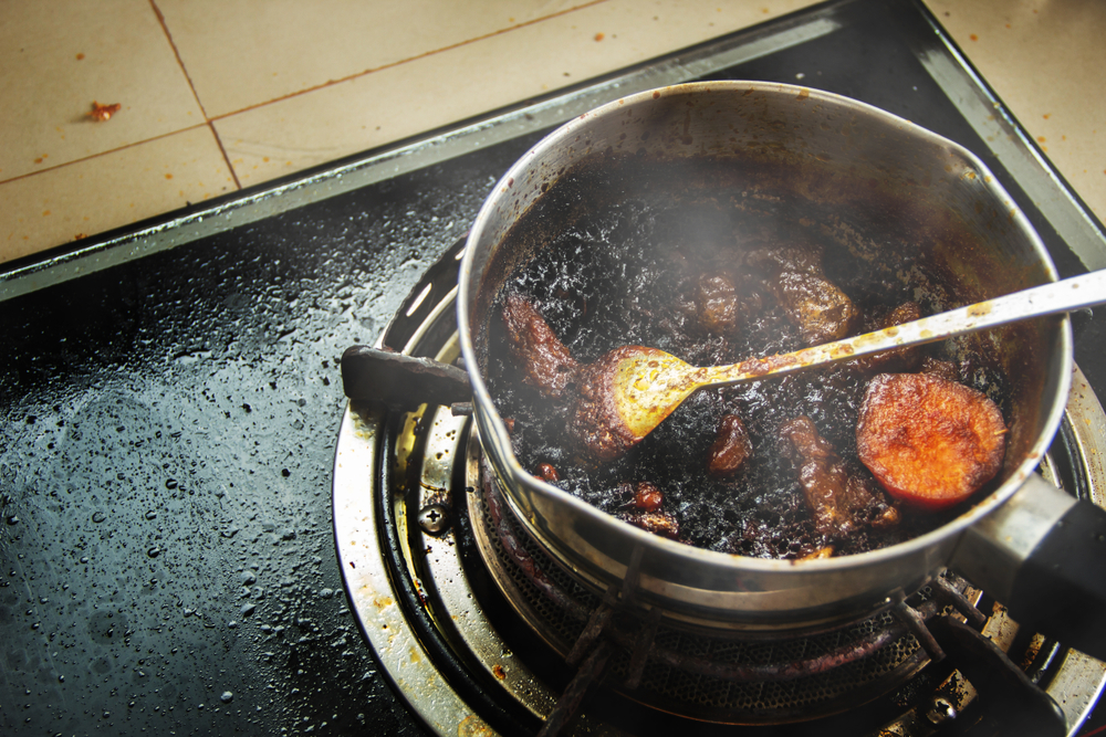 Burned food in the pot on a gas stove and full of oil stains from warming up food that is forgetful.