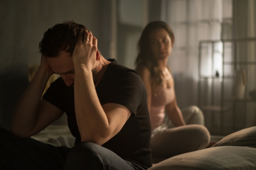 Husband and wife arguing in bed, relationship problems concept.